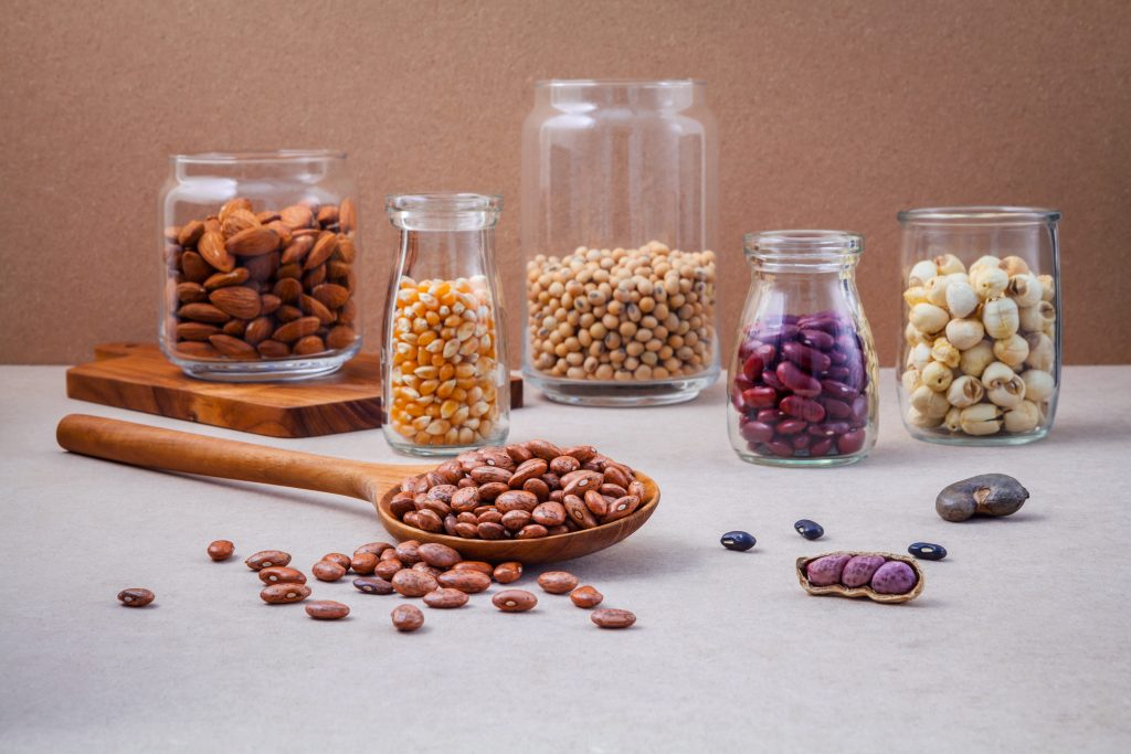 Various beans and nuts in the glass on brown background. mung bean, groundnut, red kidney bean , lotus seed ,almond,millet and brown pinto beans .