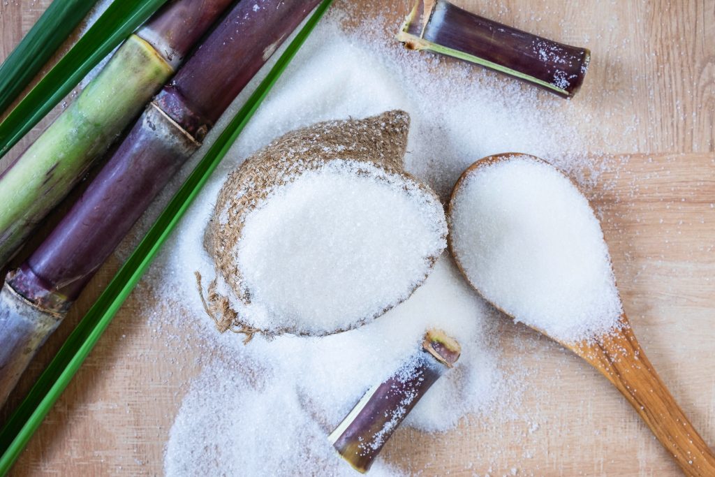 White sugar and sugar cane on the table.